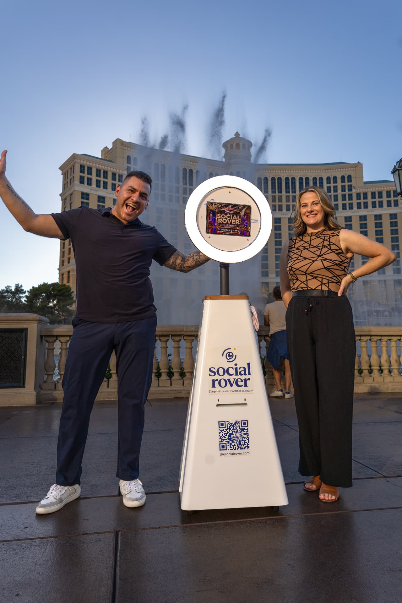 Guests posing beside The Social Rover in front of the Bellagio fountains